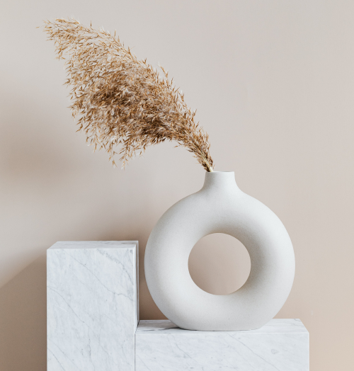 White, round, ceramic vase holding dried wheat